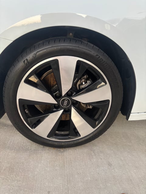 Black and white Audi alloy wheel with black tire on white vehicle body