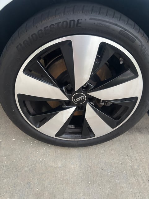 Close-up of an Audi car wheel with black and white alloy rim and Bridgestone tire on pavement