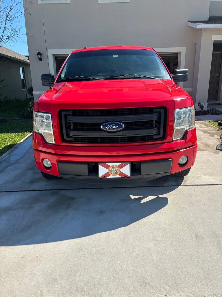 Red Ford pickup truck parked in a driveway in front of a garage
