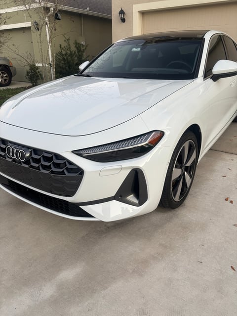 White Audi sedan parked in driveway with garage in background