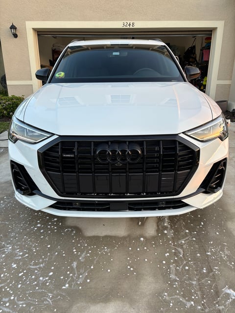 White Audi SUV parked in driveway in front of open garage with house number 3248