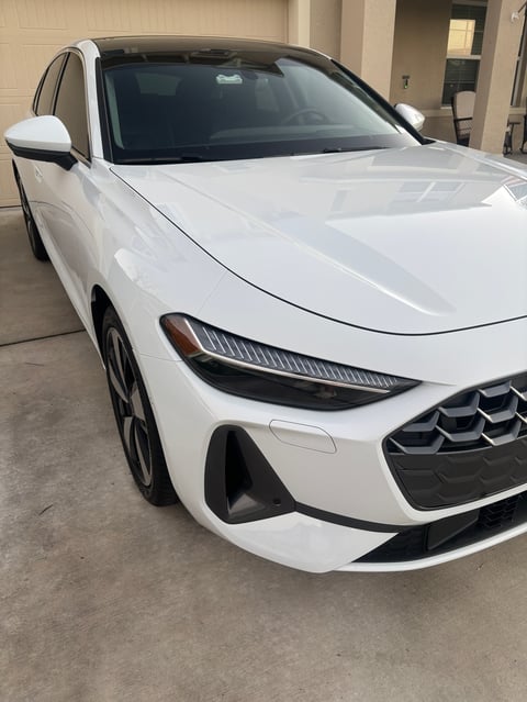 White BMW sedan parked in a garage, front quarter view showing LED headlights and grille