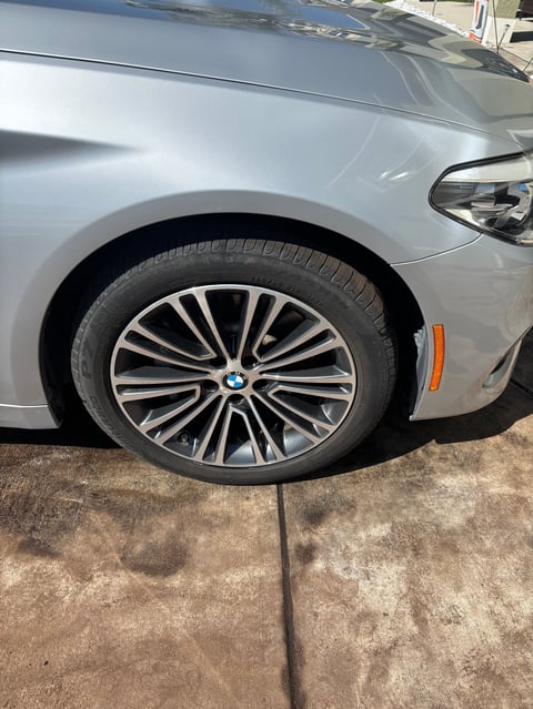 Close-up of silver BMW with multi-spoke alloy wheel and black tire, parked on concrete driveway